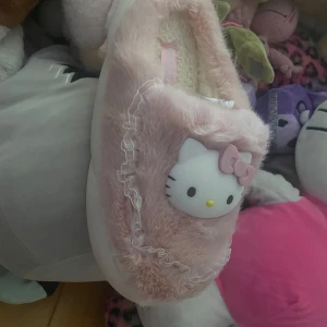 Hello Kitty fluffiga tofflor rosa - Jag köpte domhär för ett tag sen men dom är tyvärr för smà, jag har använt dom en gảng för att prova dom men dom satt inte bra pa eftersom jag har storlek 42-43 och dom är i 40-41, Supergulliga rosa tofflor med fluffig yta och Hello Kitty-ansikte framtill. Tofflorna har volangdetaljer i vitt och är fodrade med mjukt material för extra komfort. Perfekta för dig som älskar söta accessoarer och vill ha något mysigt på fötterna hemma.