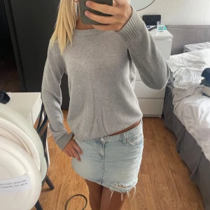 Ljusgrå stickad tröja med rund hals - Enkel och stilren ljusgrå stickad tröja med rund halsringning och ribbade muddar vid ärmslut och nederkant. Tröjan har en normal passform och är perfekt för lager-på-lager under kyligare dagar.