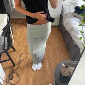 Ljusgrön långkjol i stretchigt tyg - Supersnygg ljusgrön långkjol med tight passform och enkel design. Kjolen är figurnära och har en mjuk, stretchig känsla som gör den riktigt bekväm. Perfekt att styla med crop tops eller oversized tröjor för en chill look.