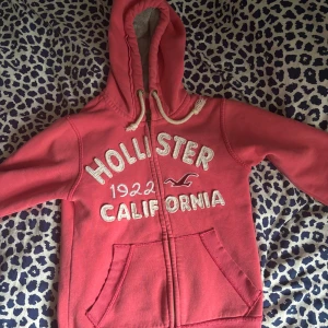 Rosa/vibröd hoodie från Hollister med dragkedja - Ziphoodie från Hollister i vinröd/rosa färg. Den har ett litet märke/ hål som man kan se på sista bilden men det märks knappt