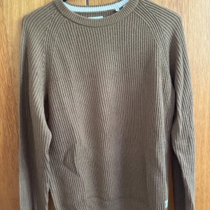 Brun stickad tröja Jack & Jones S - Säljer en brun stickad tröja från Jack & Jones i storlek S. Tröjan har ribbad struktur, rund halsringning och långa ärmar. Perfekt för dig som gillar en enkel och stilren look med lite oversized känsla.