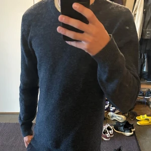 A Days March tröja - Säljer en blå stickad tröja från A Day's March i storlek M. Tröjan är gjord av 100% ull och är perfekt för kyligare dagar. Skicket är som nytt utan prislapparna kvar men säljs då den inte används. 