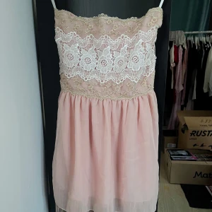 Rosa kortklänning med spetsdetaljer - Supersöt ljusrosa kortklänning köpt i Japan, bandeaustil och vackra vita spetsdetaljer upptill. Klänningen har en flowy kjol i tunn tyll och broderade gulddetaljer på överdelen. Perfekt för sommarens alla tillfällen och ger en romantisk vibe. Någon lös tråd men annars fantastiskt skick. Ingen storlekstag men passar XS/S. 