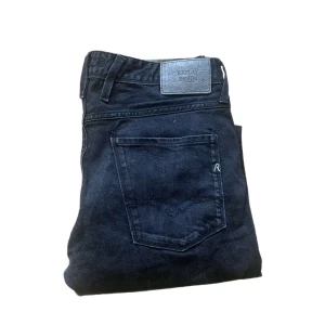 Replay Anbass jeans - Säljer ett par svarta Replay Anbass jeans i klassisk femficksmodell. Jeansen har smal passform, snygga detaljer med dragkedja vid fickan och är tillverkade i mjukt bomullsjeansmaterial. Perfekta för dig som gillar stilrena och bekväma jeans. Längd ca 110cm. Jag skickar ej bild när jag bär plaggen och jag vet ej vilken längd och vikt de passar då jag inte prövar kläderna jag säljer 😃