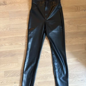 Svarta skinny byxor i skinnimitation Zara  - Snygga svarta skinny byxor från Zara i skinnimitation. Hög midja, klassiska fickor bak och dragkedjor vid bensluten för extra edge. Perfekta för dig som vill ha en stilren och trendig look med lite attityd.