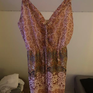 Mönstrad långklänning med snörning - Säljer en unik bohemisk långklänning med paisleymönster i olika färger. Klänningen har smala axelband, snörning framtill och markerad midja. Tunt, luftigt material som passar perfekt för varma dagar. Finns även en underklänning så att den inte är helt genomskinlig. Den är från USA och jag fick den i present men den var tyvärr för liten. Helt ny😍storlek XS men passade både mindre och lite större! 