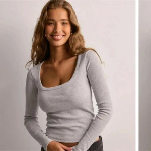 Ljusgrå långärmad topp med fyrkantig ringning - Säljer en ljusgrå långärmad topp med snygg fyrkantig ringning. Modellen är figurnära och passar perfekt till jeans eller kjol. Mjuk och stretchig bomullsblandning som känns skön mot huden.