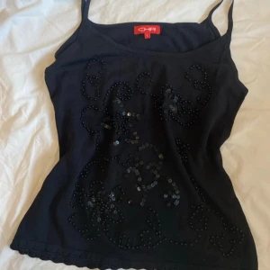 Svart paljettlinne  - Svart linnetopp från CHR med smala axelband och dekorativa svarta paljetter framtill i ett blommigt mönster. ❣️❣️Passar storlek m-l