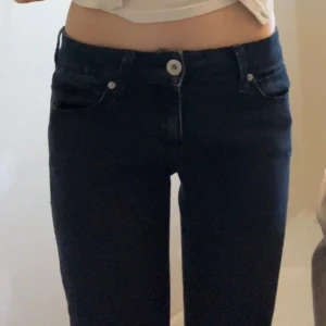 Mörkblå bootcut jeans från Guess💗 - Snygga mörkblå jeans från Guess med klassisk femficksdesign och bootcut-ben. Jeansen har hög midja och är tillverkade i stretchigt denim för en bekväm passform. Diskret Guess-logga på bakfickan. Perfekta för dig som gillar en tidlös look. Köpta i USA. 