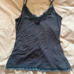 Svart linnetopp med spetsdetaljer - Svart linnetopp med tunna axelband och v-ringad halsringning dekorerad med svart spets😍. Nedtill finns en fin spetskant som ger en extra touch. Perfekt att styla lager på lager eller som den är. Har två stycken och säljer båda två!❤️Står ingen storlek men passar mig med S!❤️
