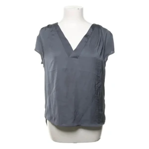 Classy grå blus  - Snygg grå blus från H&M Conscious med v-ringning och korta ärmar. Tillverkad i ett mjukt, silkesliknande material som ger en lyxig känsla. Perfekt att styla med jeans eller kjol för en clean look.