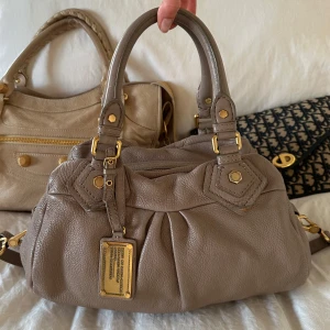 Beige Q Classic Baby Groove väska! - Köp helst via min vinted, billigare pris pga lägre avgifter @juliavallberg 🤍 Snyggaste beigea handväskan i äkta läder från Marc by Marc Jacobs. Den ikoniska modellen Q Classic Baby Groove! En populär och eftertraktad vintagemodell med gulddetaljer och dubbla handtag. Väskan är i fint skick med lite slitage på lädret vid handtagen men inget som syns tydligt. Helhetsintrycket är mycket välbevarat. Mått: 34x18x12 cm (undersida) Kan hämtas hemma hos mig i Nacka eller skickas 🤍