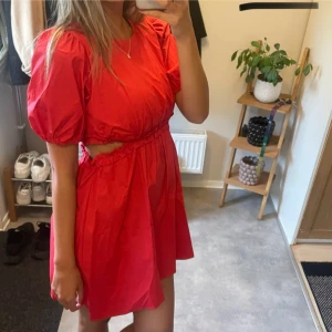 Röd kort klänning med cut out - Superfin röd kort klänning med puffiga korta ärmar och cut out-detalj i midjan.  Aldrig använd!! Klänningen är i barnstorlek men passar för någon som har storlek xs/s.💕