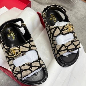 Valentno sandaler med grafiskt mönster - Snygga sandaler från Valentno med svart och beige grafiskt mönster. Skorna har öppen tå, platt sula och justerbara remmar med guldiga logodetaljer. Tillverkade i textil och skinn för en lyxig känsla och cool look.