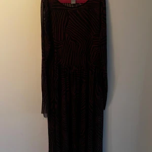 Svart och brun zebramönstrad klänning Lindex - Snygg långklänning från Lindex i svart och brun zebramönstrad mesh. Klänningen har långa, transparenta ärmar och en lös passform som ger en cool och avslappnad vibe. Katt finns i hemmet, kontakta vid fler frågor🌷