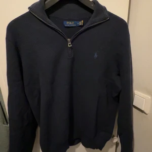 Marinblå  Ralph Lauren halfzip - Säljer en Ralph Lauren halfzip i marinblå färg med broderad blå hästlogga stilren och diskret klassiker från Polo Ralph Lauren.   Storlek: M(normal i passform)   Skick: Mycket fint inga hål, noppor eller  fläckar   Färg: marinblå med blå broderad logga   Äkthet: Garanterat äkta – detaljer som taggar, tyg och brodyr styrker detta (se bilder) Pris: 500 kr