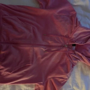 Rosa hoodie med dragkedja och huva - Säljer en rosa hoodie med dragkedja och huva. Tröjan har stora fickor framtill och snörning i huvan. Perfekt för dig som gillar en chill och avslappnad stil. Passar lika bra till jeans som till mjukisbyxor.