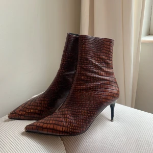 Bruna boots med krokopräglat mönster - Snygga bruna boots med spetsig tå och låg klack. Skorna har ett krokopräglat mönster. Perfekta för dig som vill sticka ut med en edgy vibe och gillar detaljer som sticker ut. Finns några skavanker men annars i bra skick💗