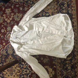 Vit skjorta från Oscar of Sweden - Säljer en stilren vit skjorta från Oscar of Sweden i slim fit. Skjortan har långa ärmar och knappar framtill. Perfekt för en elegant look utan att behöva stryka den, tack vare non-iron materialet.