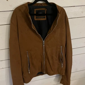 Brun mockajacka från Zara - Snygg brun mockajacka från Zara med dragkedja framtill och på fickorna. Jackan har långa ärmar med dragkedjor vid ärmsluten. Tycker verkligen att denna är sååå snygg men är tyvärr för stor:/