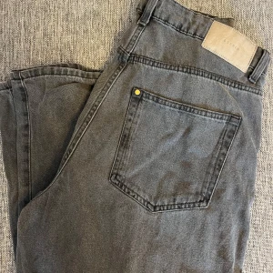 Grå mom jeans från Hm - Snygga grå mom jeans från HM med ultra hög midja och ankellängd. De har en loose passform och klassisk femficksdesign. 