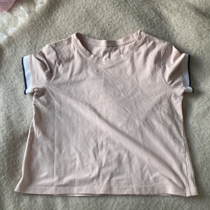 Beige t-shirt från H&M - Säljer en beige t-shirt från H&M i ekologisk bomull. T-shirten har korta ärmar med kontrasterande kant i mörkblått och vitt. Perfekt för en avslappnad stil. 🌟