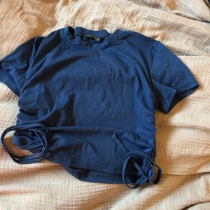 Blå T-shirt  - T-shirt storlek S, snygg färg och snörning i sidorna!