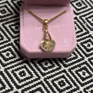 Guldhalsband med kristallhänge - Elegant guldhalsband med ett vackert kristallhänge. Hänget har en unik form och fångar ljuset fint. Perfekt för att ge en touch av glamour till din outfit.