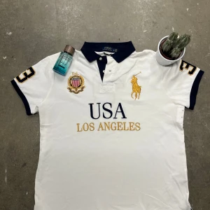  Ralph Lauren Polo USA Los Angeles (L) - Säljer en vit pikétröja från Ralph Lauren. Unik och stilig. Det finns inte många av dem. Den har dock en gul fläck på baksidan( som går av)  Priset kan såklart diskuteras 🙌🏼