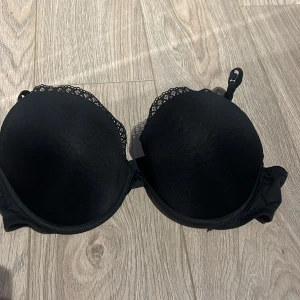 Svart bh med spetsdetaljer - Säljer en elegant svart bh med spetsdetaljer längs kanterna. Den har justerbara axelband och en slät design för en bekväm passform. Perfekt för att känna sig både bekväm och stilren.