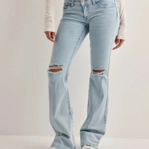 Ljusblå bootcut lågmidjade jeans med slitningar/hål - Snygga ljusblå bootcut jeans med slitningar på knäna och broderade detaljer på bakfickorna. Säljer då de inte kommer till användning, använda ungefär 5 ggr så superbra skick! pris går att diskutera!! köpta för 700💕💕💗