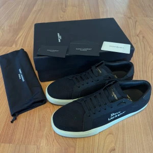 Saint Laurent EU 42-43 - Snygga svarta sneakers från Saint Laurent med vit sula och diskret logga på sidan.Levereras med originalförpackning och dustbag. Hör av er vid ytterligare frågor eller diskution om pris