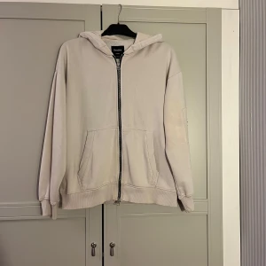 Beige hoodie från Bershka - Säljer en stilren beige hoodie från Bershka. Den har en dragkedja framtill och praktiska fickor. Perfekt för en avslappnad look.