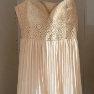  ljusrosa klänning  - Säljer en elegant väldigt ljusrosa/beige klänning med spetsdetaljer upptill och plisserad kjol. Klänningen har en v-ringad design och är ärmlös, perfekt för sommarens festligheter. Vid fler bilder så är det bara att fråga💕