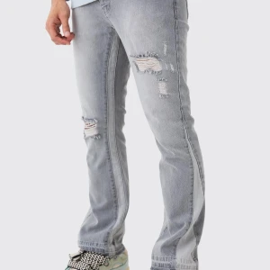 Grå flare jeans med slitningar - Snygga grå jeans med coola slitningar på låren och knäna. Perfekt för en avslappnad stil. De har en straight passform och är tillverkade i jeansmaterial.