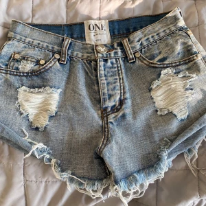 Lågmidjade Jeansshorts från One Teaspoon stl xs  - Säljer ett par coola jeansshorts från One Teaspoon med slitna detaljer och fransar. Stl 26 passar xs. Tyvärr för små💞