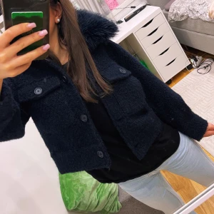 Marinblå jacka från Gina Tricot - Säljer en snygg marinblå jacka från Gina Tricot med fluffig krage och knappar framtill. Jackan har en cool, lite boxig passform och är perfekt för kyligare dagar. Den har två fickor med lock på bröstet och långa ärmar. Perfekt för att hålla stilen i höst och vinter! 🖤använd 1 gång 