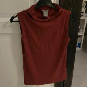 Röd ribbad ärmlös topp - Säljer en snygg röd ribbad topp i storlek XS. Den har hög krage och tight passform. Aldrig använd ❤️