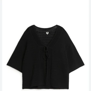 Svart stickad kofta med knyt - Svart stickad kofta med v-ringning och knyt framtill.