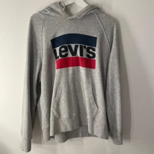 Grå hoodie från Levi's - Säljer en grå hoodie från Levi's med deras logga i blått och rött på bröstet. Ska flytta snart så vill gärna bli av med allt så fort som möjligt (pris kan diskuteras)💕