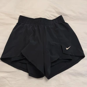 Svarta träningsshorts från Nike - Svarta träningshorts från Nike med innershorts som är bekvämt när man löper för att slippa skavsår på låren. Bekväm passform och är gjorda i ett lätt syntetmaterial som andas. Knappt använda.