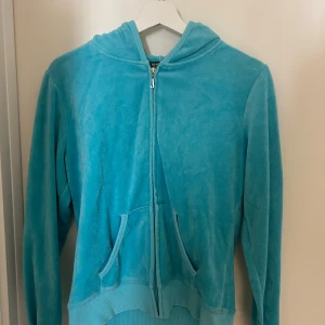 Kofta från Juicy Couture - Säljer en snygg turkos hoodie från Juicy Couture med dragkedja och huva. Baksidan har en glittrig Juicy Couture-logga med en krona. Koftan är använd fåtal gånger och har inget tecken på användning. Plagget är i storlek 3XL men passar mig som bär M/S💕Bara kontakta i DM om ni har frågor eller vill se bild på! 
