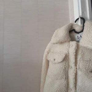 Vit teddyjacka från LA, nakd - Mysig vit teddyjacka från LA, Linn Ahlborgs kollektion,med krage och knappar framtill. Perfekt till våren.