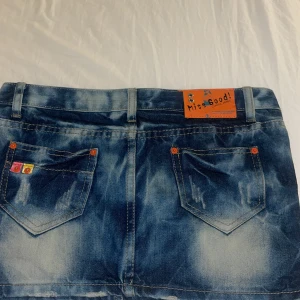Blå jeanskjol från Miss Good - INTRESSEKOLL på min favorit kjol från Miss Good med en cool tvättad look. Kjolen har orangea detaljer och knappar. Perfekt för en avslappnad stil. Liten sliten på vänster framficka, se bild 4.