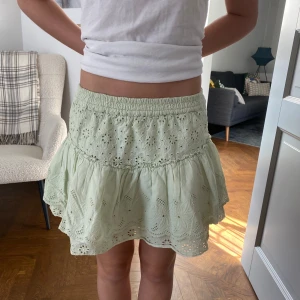 Ljusgrön kjol med volang - Charmig ljusgrön kjol med volangdetaljer och broderat mönster. Perfekt för en somrig look. Elastisk midja för bekväm passform.