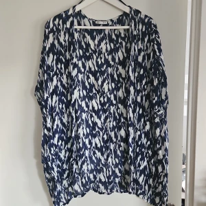 Mönstrad kofta från Cubus  - Säljer en snygg kofta från Cubus med ett blått och vitt mönster. Koftan har en lös passform och är perfekt för en avslappnad stil. Den är tillverkad i ett lätt och luftigt material.