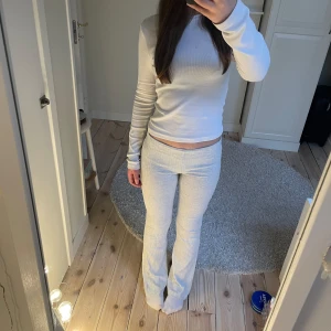 Vita ribbade byxor - Snygga vita ribbade byxor med medelhög midja och bootcut-stil. Perfekta för en avslappnad look. De är stretchiga och bekväma, vilket gör dem till ett bra val för vardagsbruk.