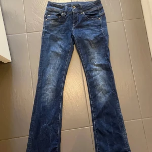 Blå jeans från G-Star RAW bootcut - Hej! Jag säljer dessa snygga jeans från G-star. Dem är lågmidjade och har en cool detalj där back, jeansen är i stretchig material vilket gör dem sköna. Dem har inte använts på länge och därmed säljer jag dem💗