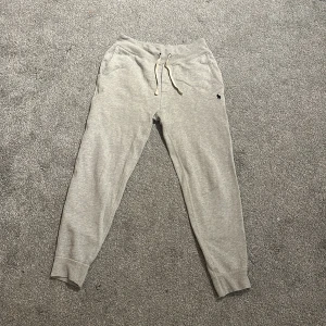 Grå mjukisbyxor från Polo Ralph Lauren - Snygga grå mjukisbyxor från Polo Ralph Lauren med dragsko i midjan och klassisk broderad logga på benet. Byxorna har ribbade muddar vid bensluten och är tillverkade i mjuk bomullsmix för extra komfort. Perfekta för chill dagar eller när du vill vara bekväm.