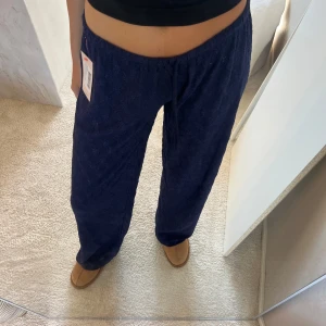 Mörkblå byxor från Nelly - Säljer ett par mörkblå byxor med snyggt spetsmönster och avslappnad passform. Byxorna har resår i midjan och vida ben, vilket gör dem riktigt sköna och trendiga. Perfekta att styla med en crop top eller hoodie för en chill look. 349kr nypris 